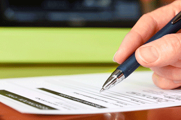 Hand holding a pen and filling out a paper application