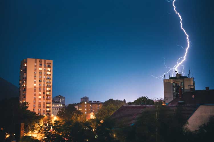 Lightning striking tall building in city at night.