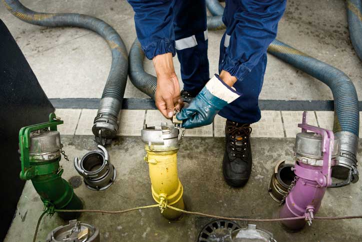 A gloved person working at fuel pipes