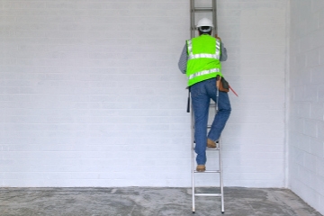 Construction worker climbing ladder in empty room mobile view