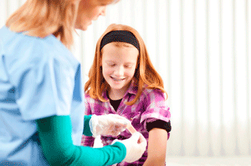 Nurse applying a band aid to a smiling young girl
