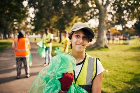 Summer worker collecting trash while wearing a high visibility vest mobile view