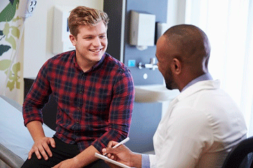 Man with blonde hair wearing a plaid shirt smiling while talking with a occupational doctor. mobile view