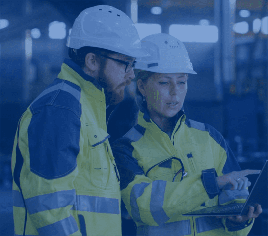 Man and woman in safety vests looking at a tablet in a manufacturing facility