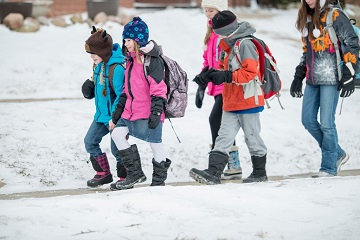 A group of children walking to school in the snow. mobile view