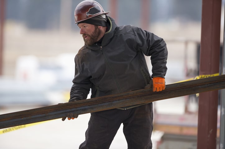 Construction worker dressed warm holding a heavy load mobile view