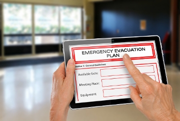 A pair of hands holding an iPad that says Emergency Evacuation Plan