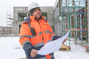 Construction worker looking at a manifest at a winter site