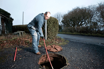 Plumber using a hosed tool to clean a sewage line