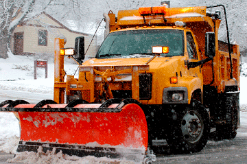 Industrial truck with snow plow plowing snow on an urban street